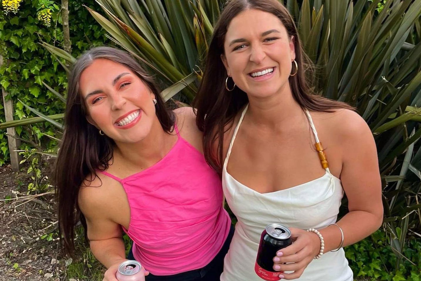 Two girls smile at the camera outdoors